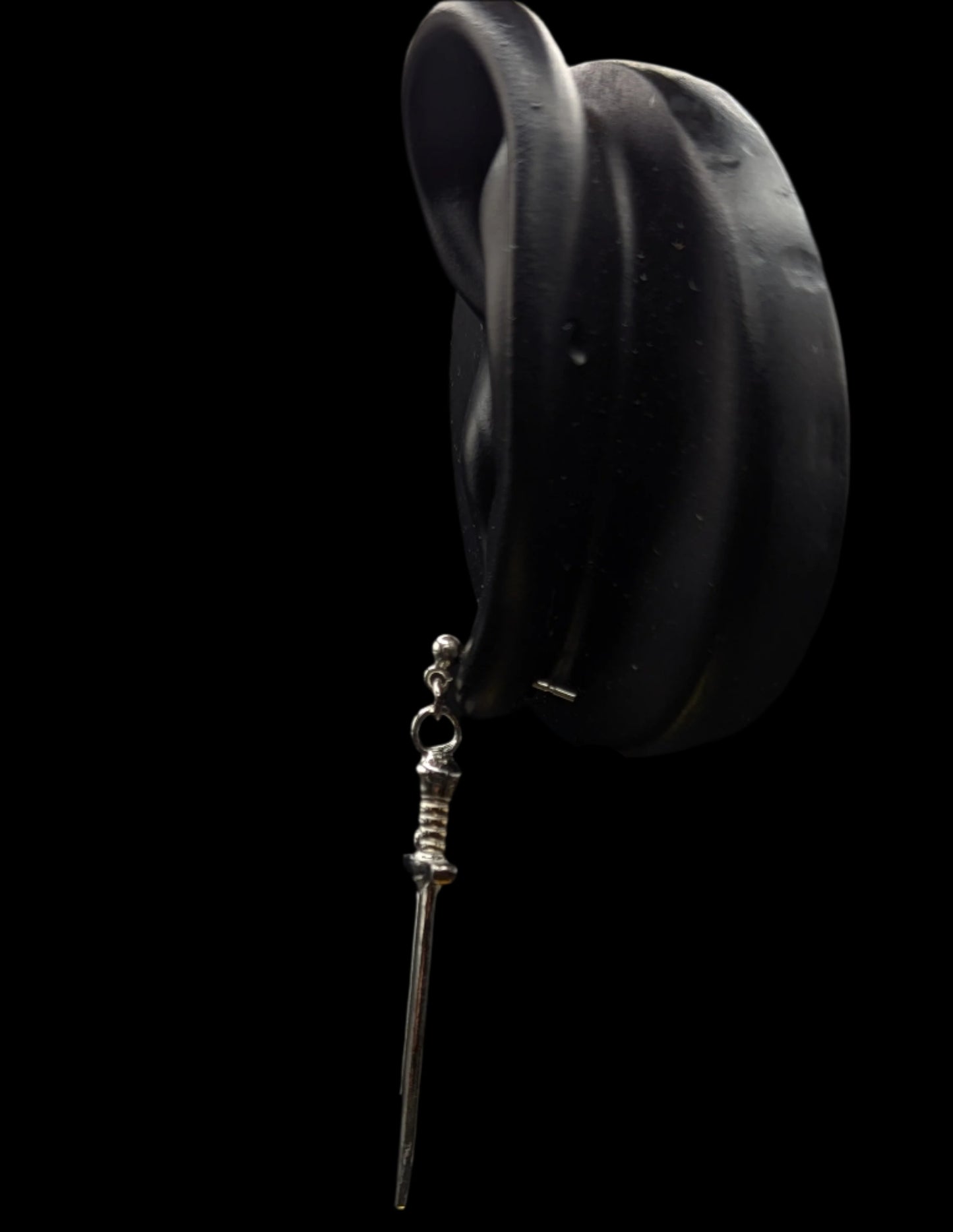 Black hat with a decorative stickpin on a black background