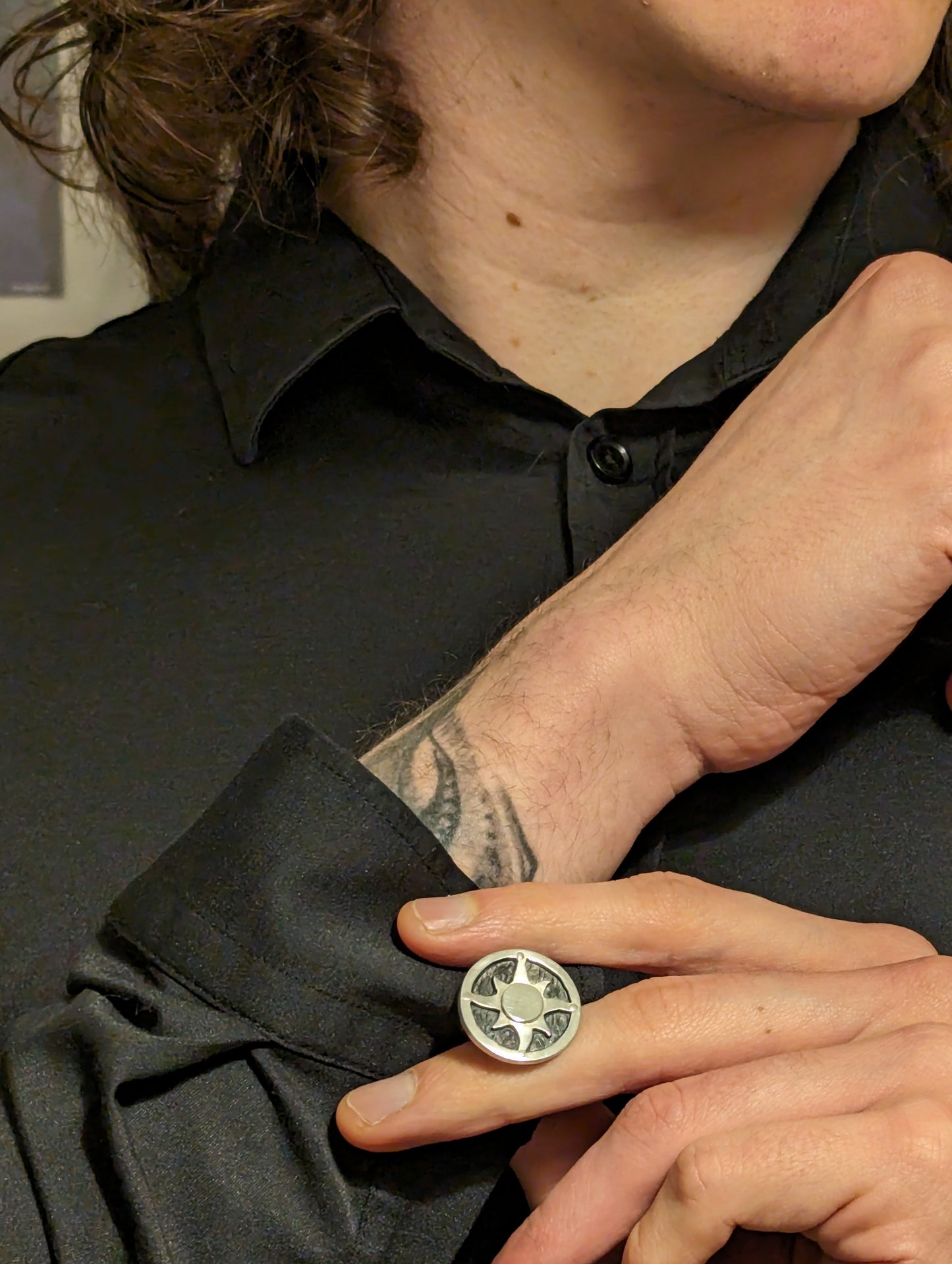 Model wearing sunwheel shield cufflinks with a black shirt