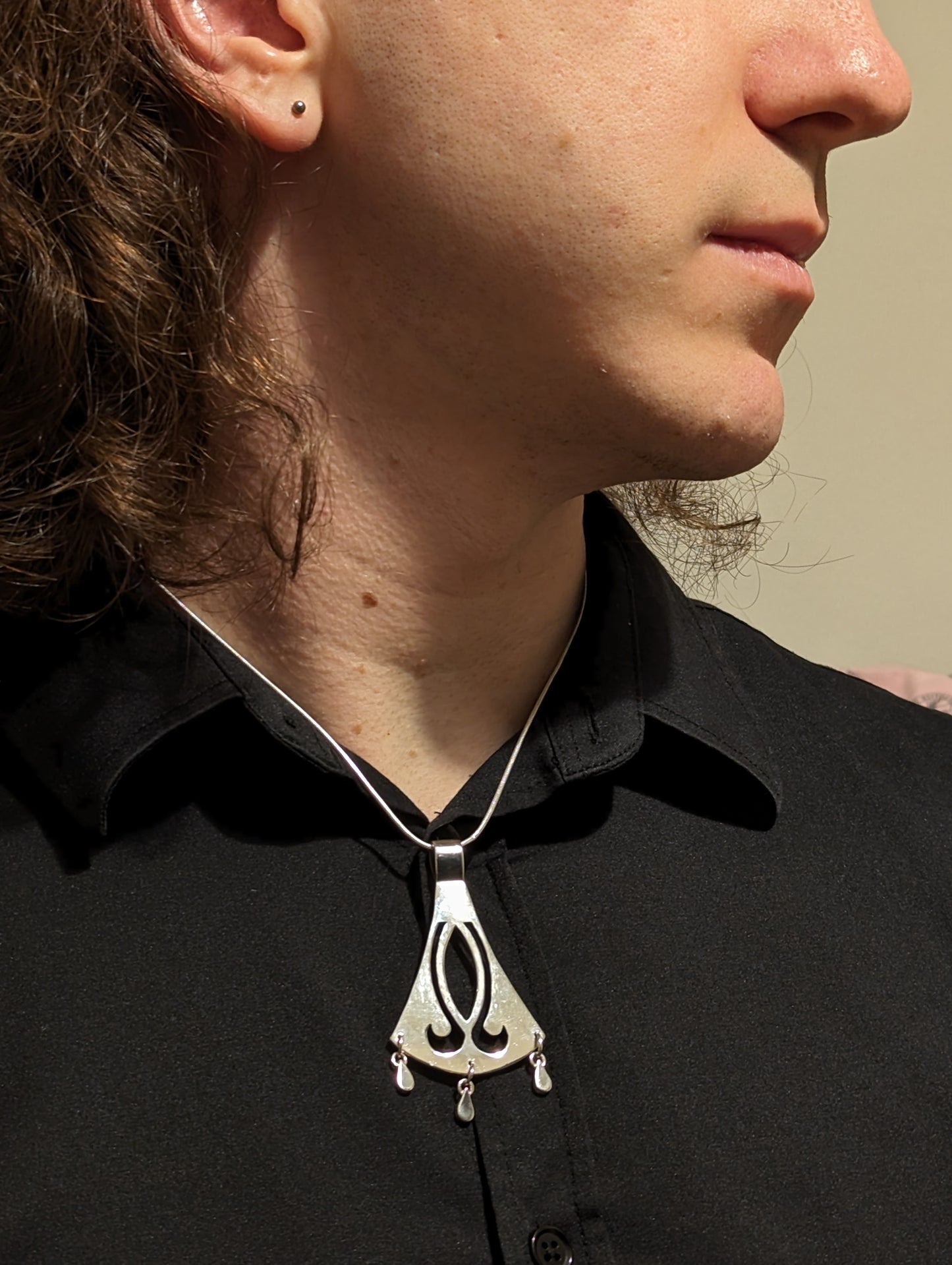 Model wearing mistborn axe necklace with a black shirt