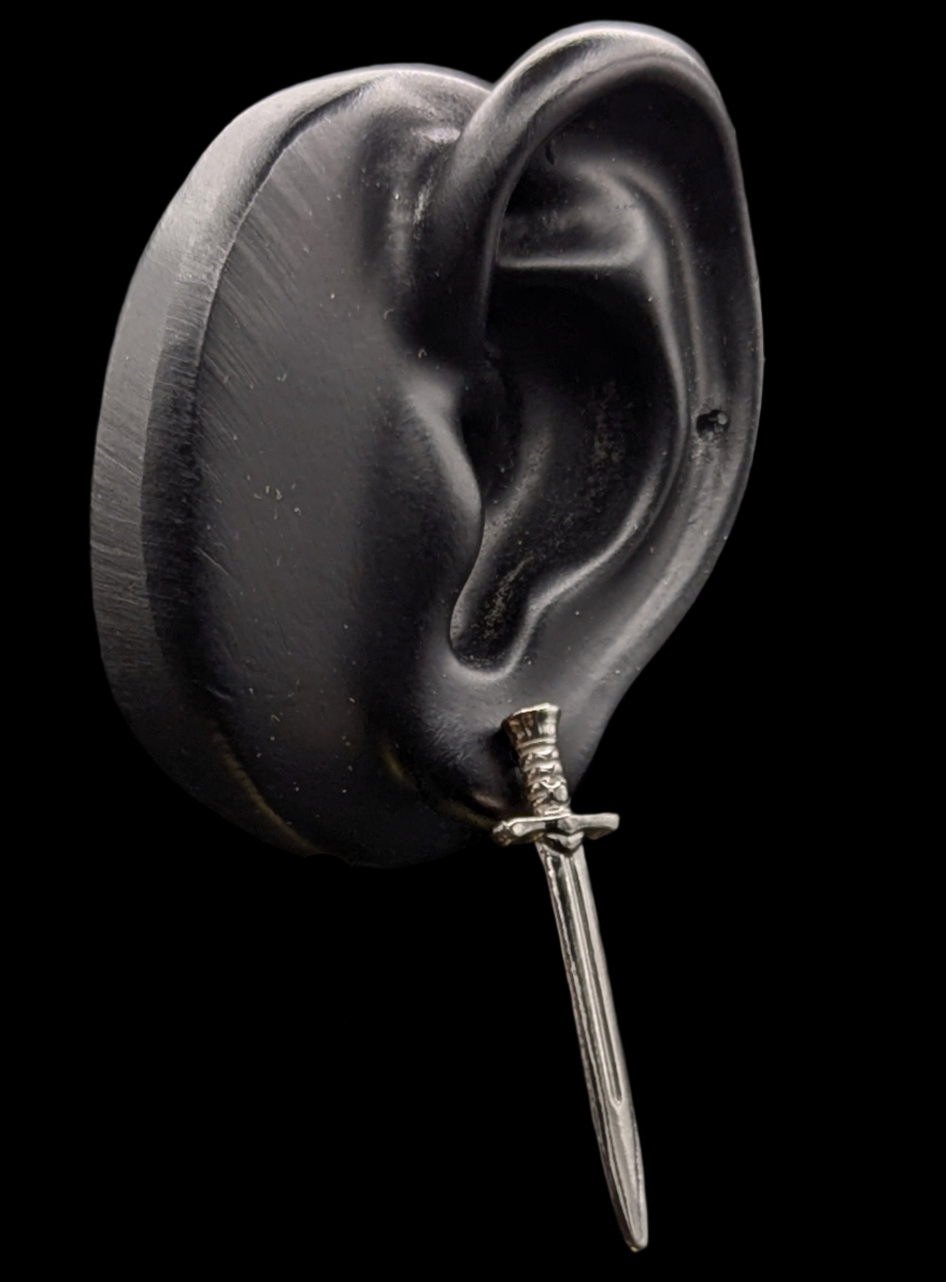 Silver dagger earring on a black background