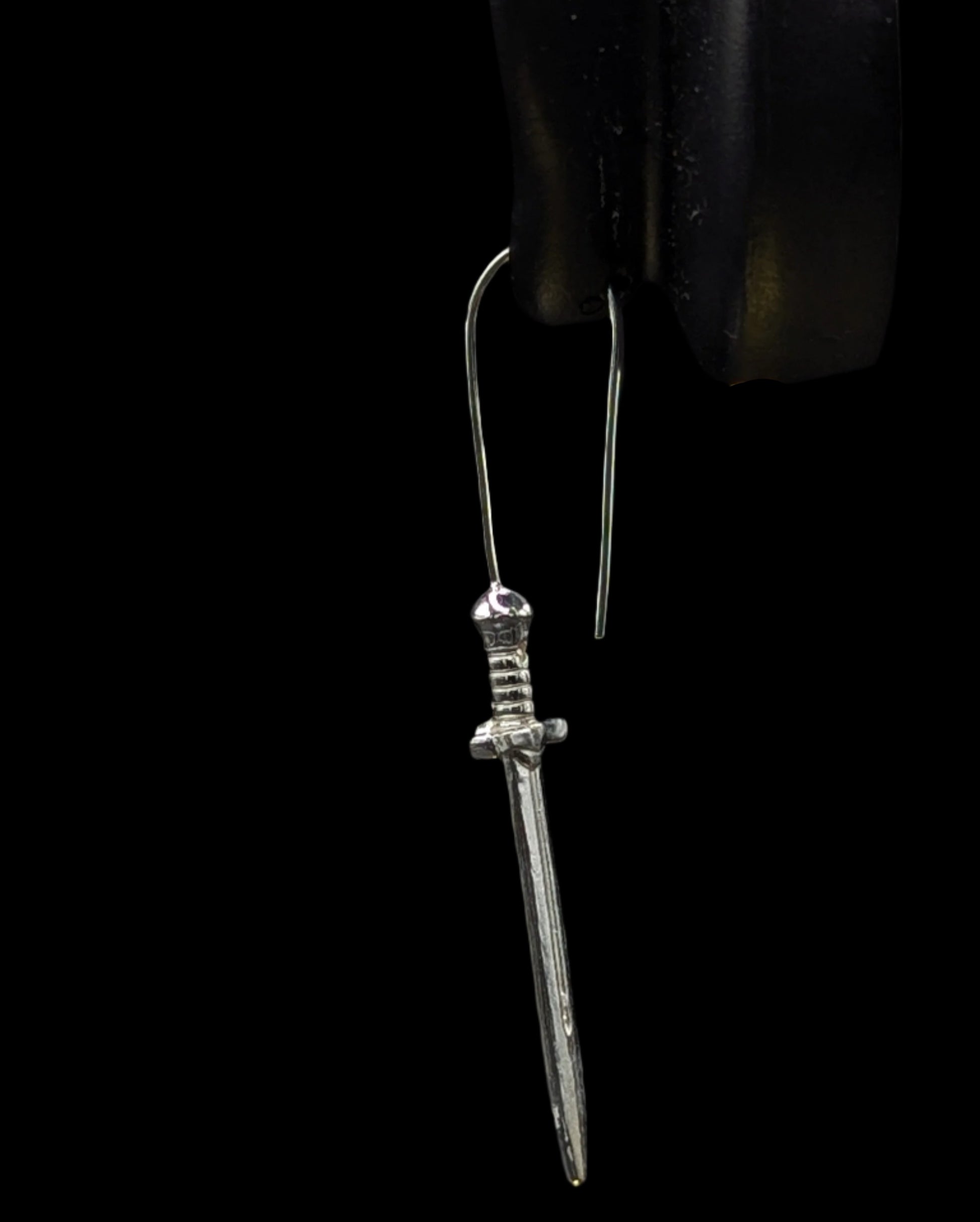 Silver dagger-shaped earring on a black background