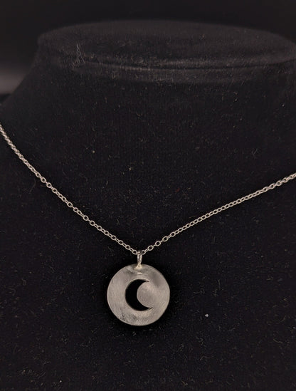 Silver necklace with a crescent moon pendant on a black background