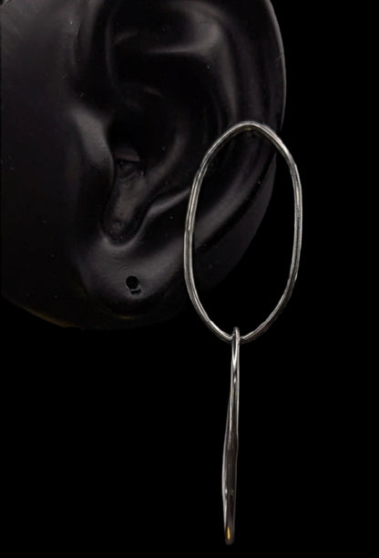 Silver hoop earring with a dangling element on a black background
