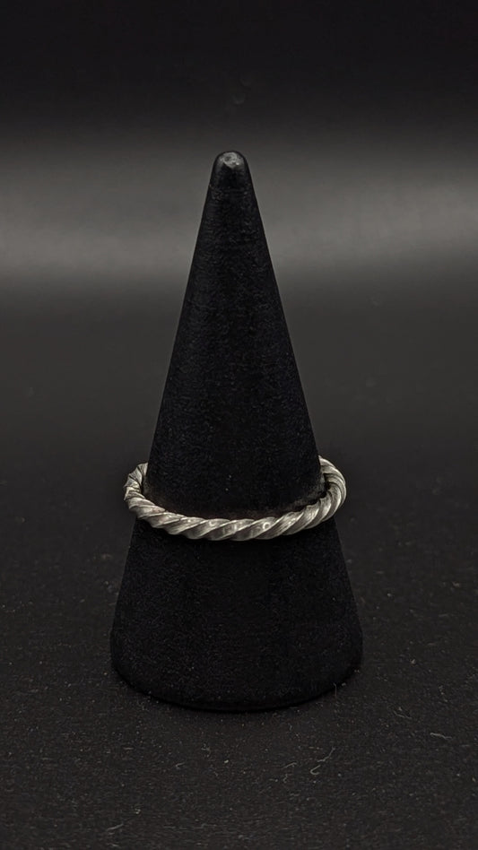 Black cone-shaped object with a silver ring on a dark background