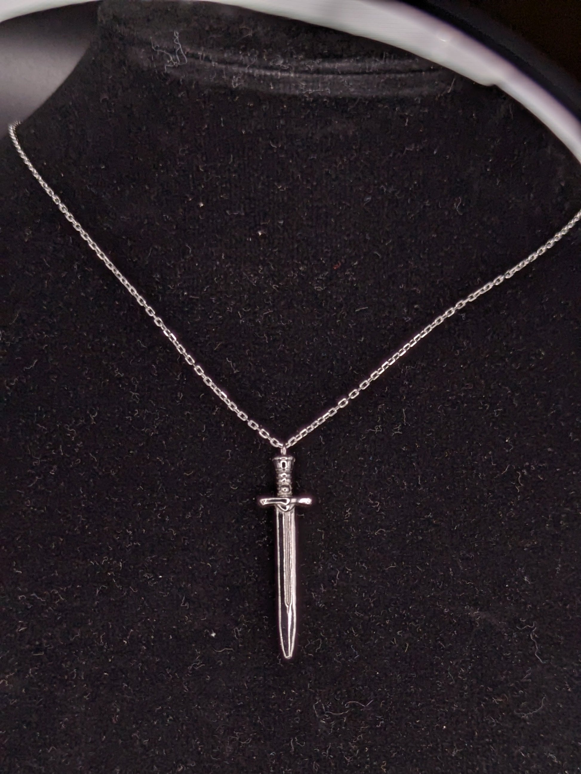 Silver dagger necklace on a black velvet stand