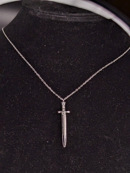 Silver dagger necklace on a black velvet stand