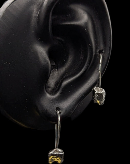 Close-up of earrings on a black ear model with a dark background